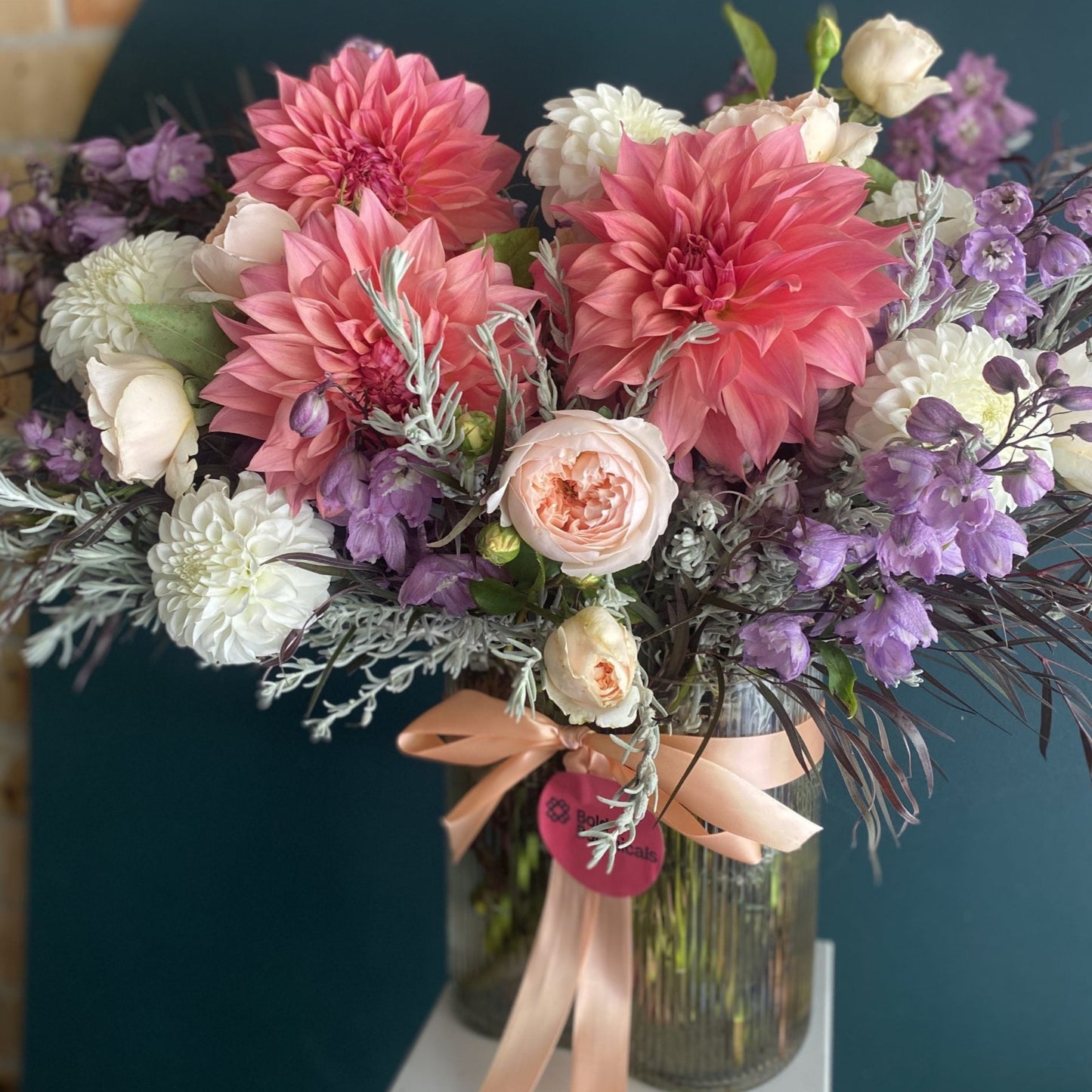 A Large sized Bold Betty seasonal flower arrangement in a ribbed vase and ribbon