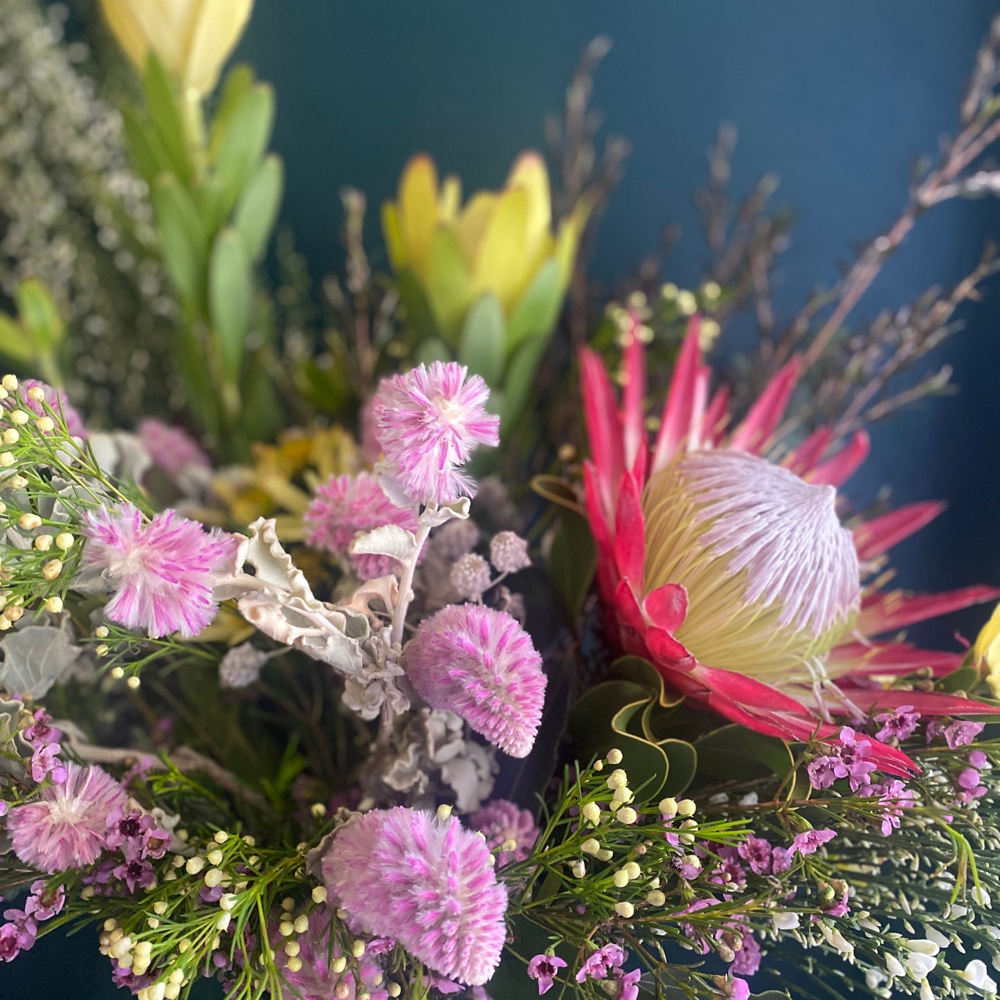 Bright, colourful flower arrangement with a protea as the focal point