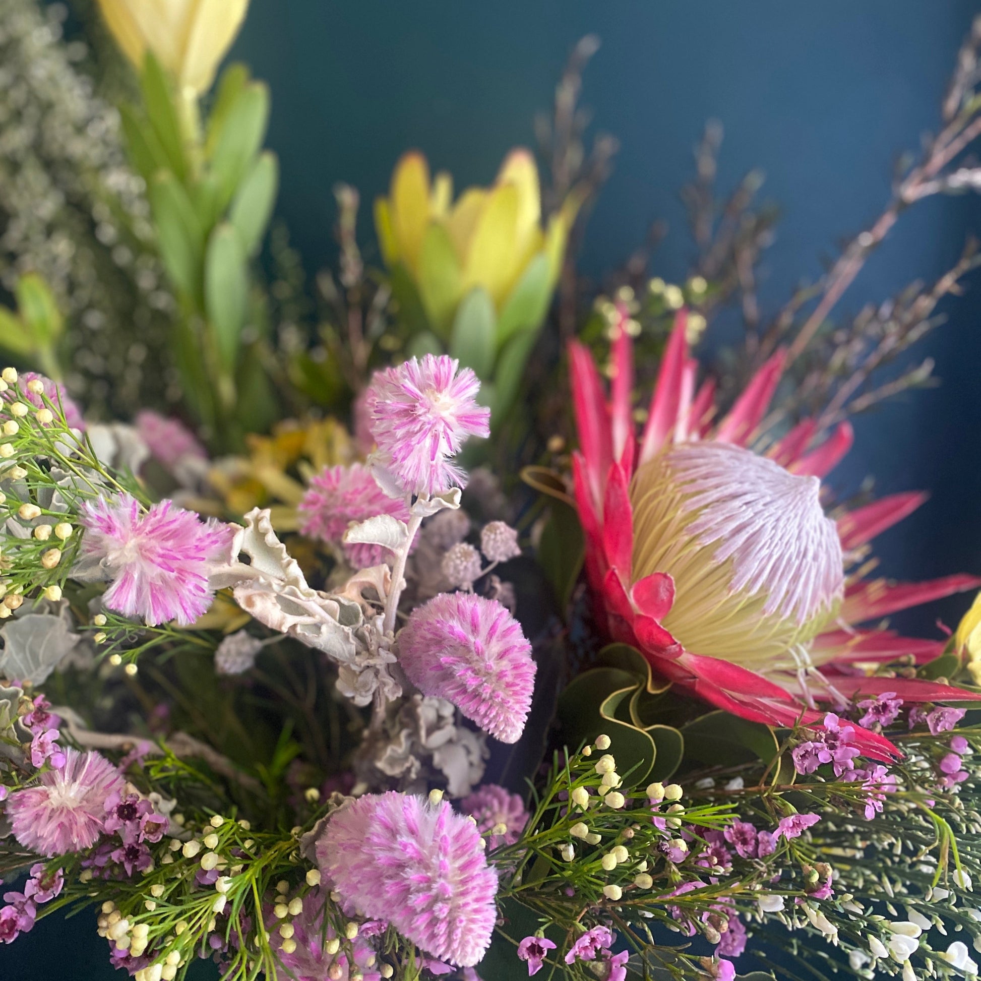 Bright, colourful flower arrangement with a protea as the focal point