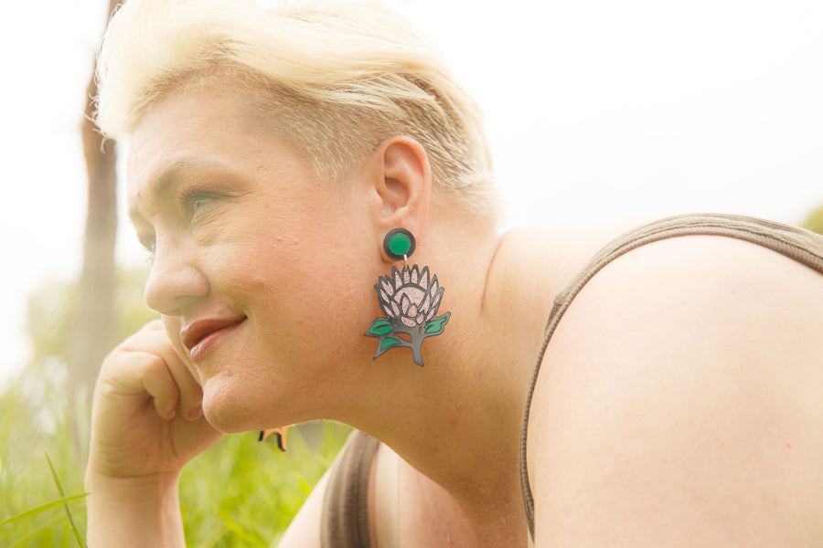 Doodad x Fandango pink glitter Waratah design earrings on a model