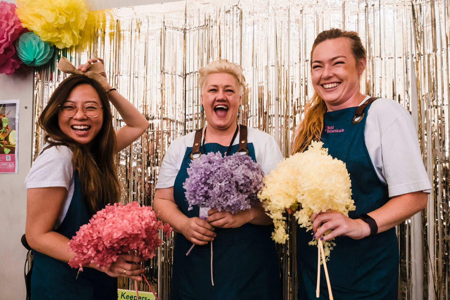 Suz and two friends smiling holding bunches of flowers