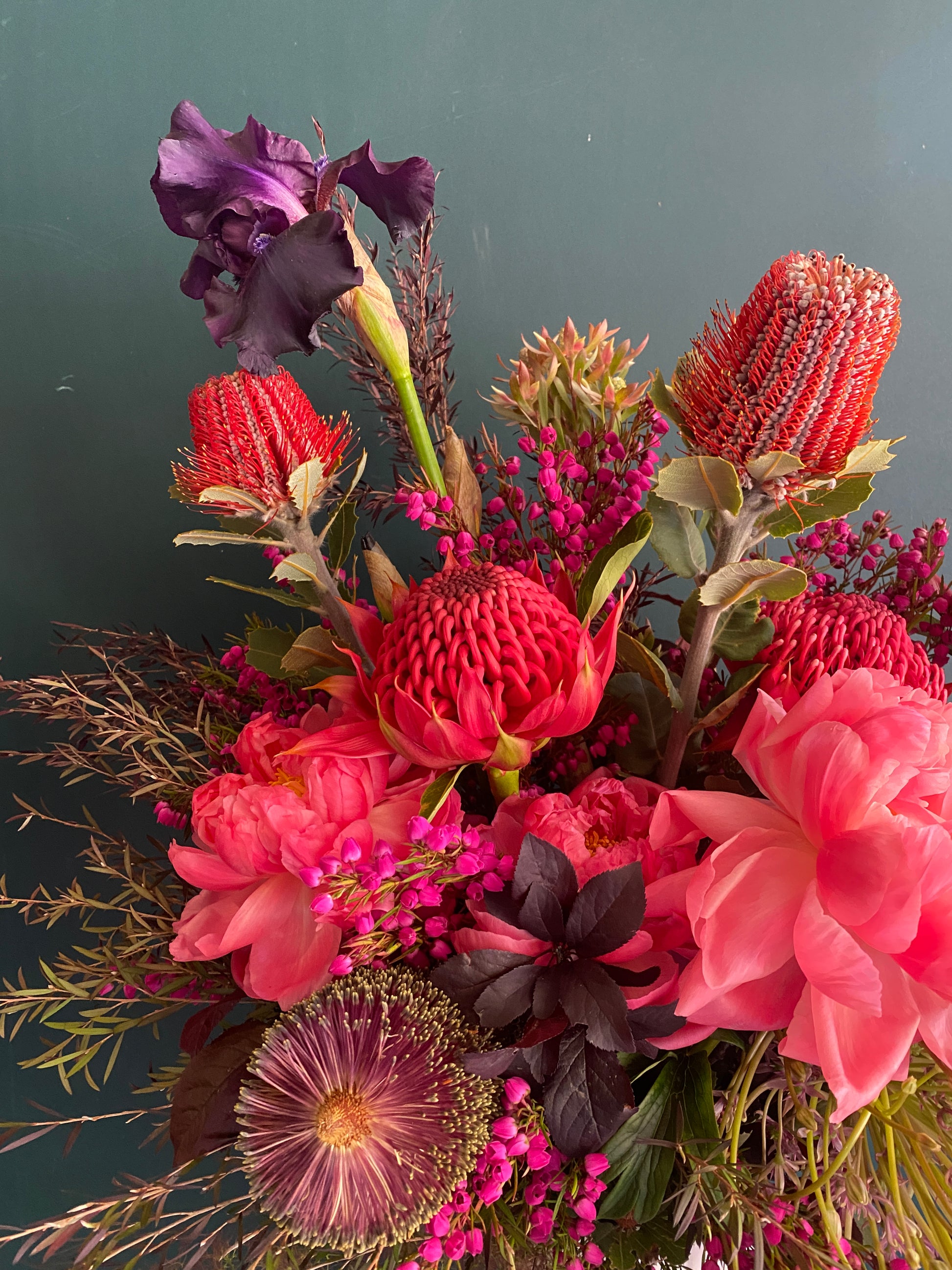 Bright red peonies mix with other red flowers within arrangement