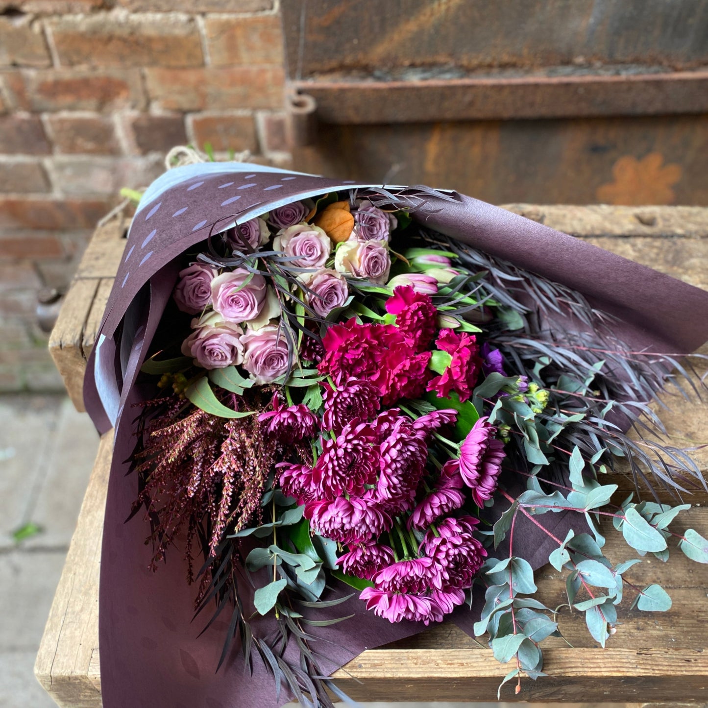 A bright floral bouquet of red, pink and purple flowers arranged by Bold Botanicals