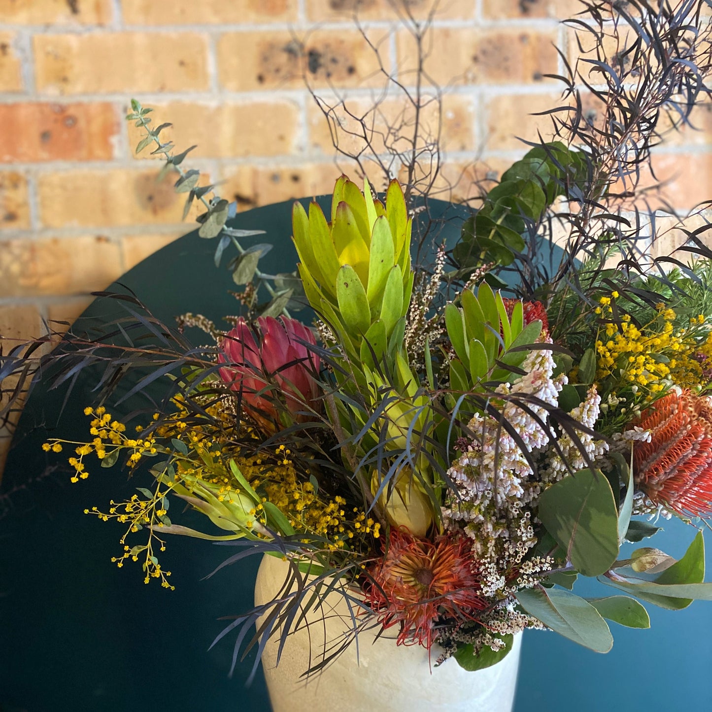 An arrangement of native Australian flowers in a white vase
