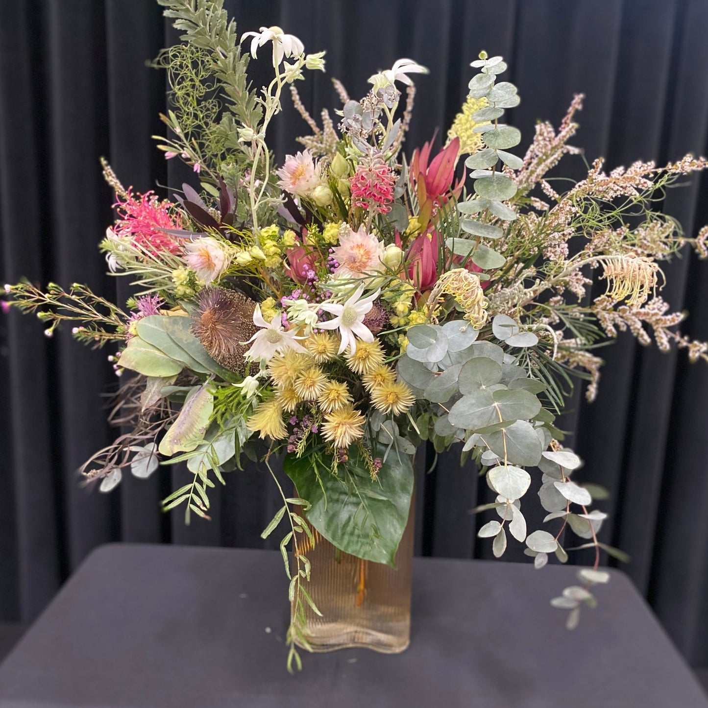 A display of bright, colourful flowers in a rippled, glass vase
