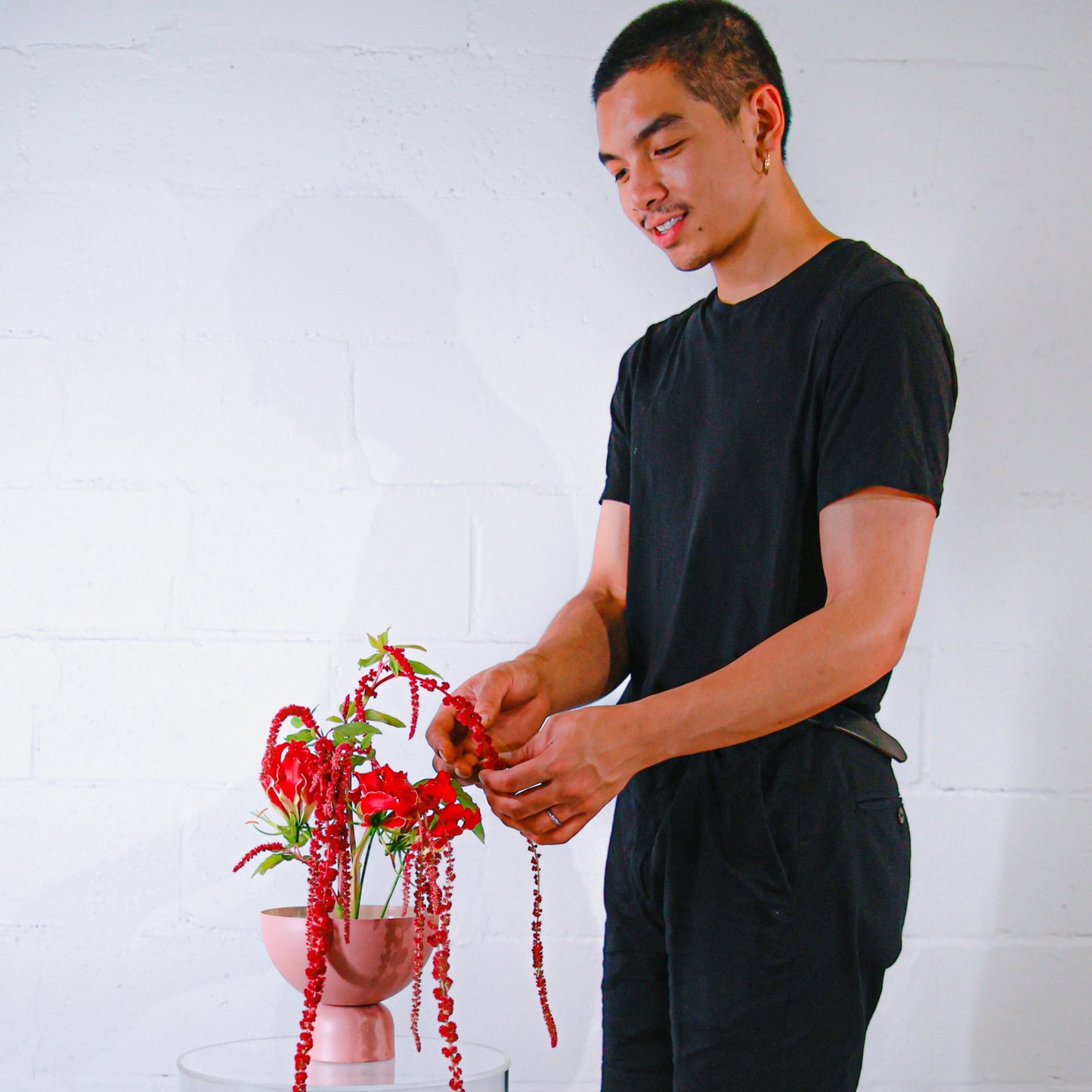 Student florist works on a red flower arrangement in studio