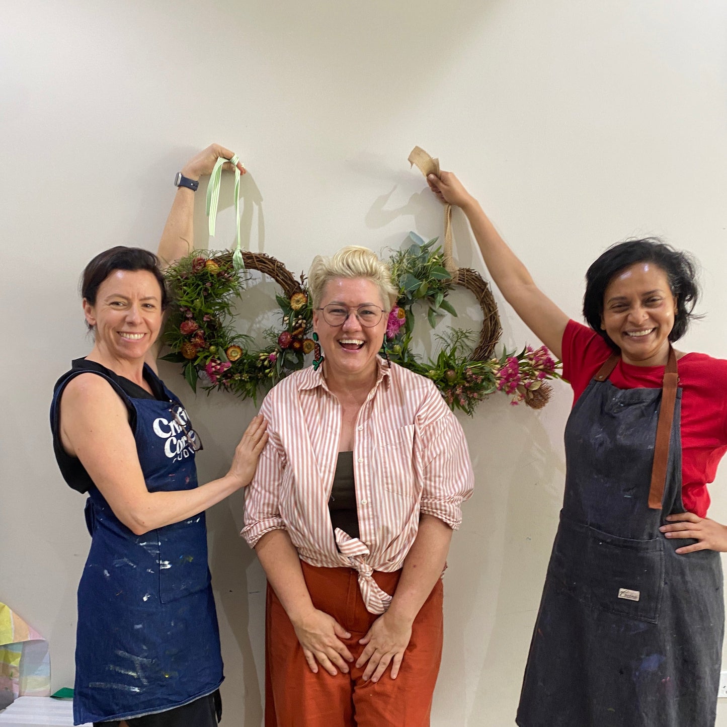 Team of women showing off their completed Christmas wreaths with florist and educator Suzanne from Bold Botanicals.