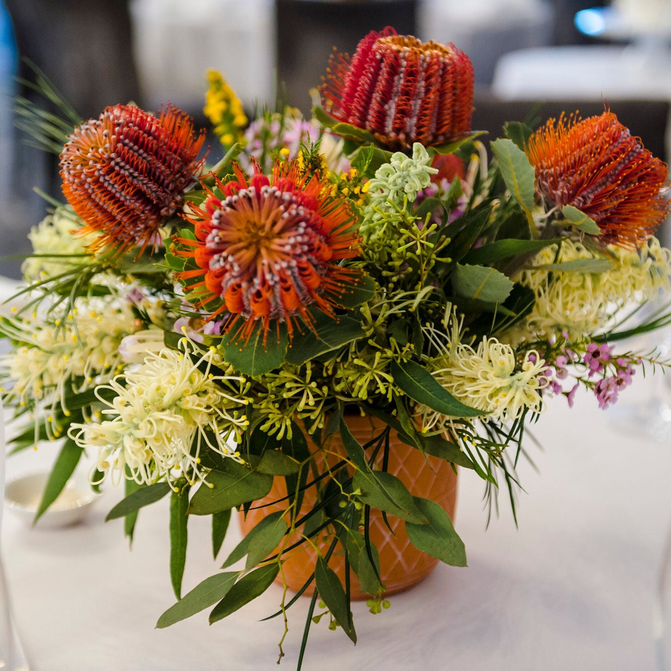 A native Australian flower table arrangement with red bottlebrush and yellow wattle made by Bold Botanicals