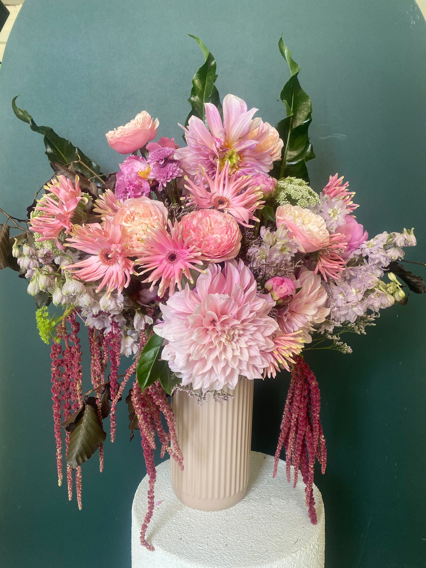 Bouquet of pink and purple flowers with a ceramic vase on a green backrop