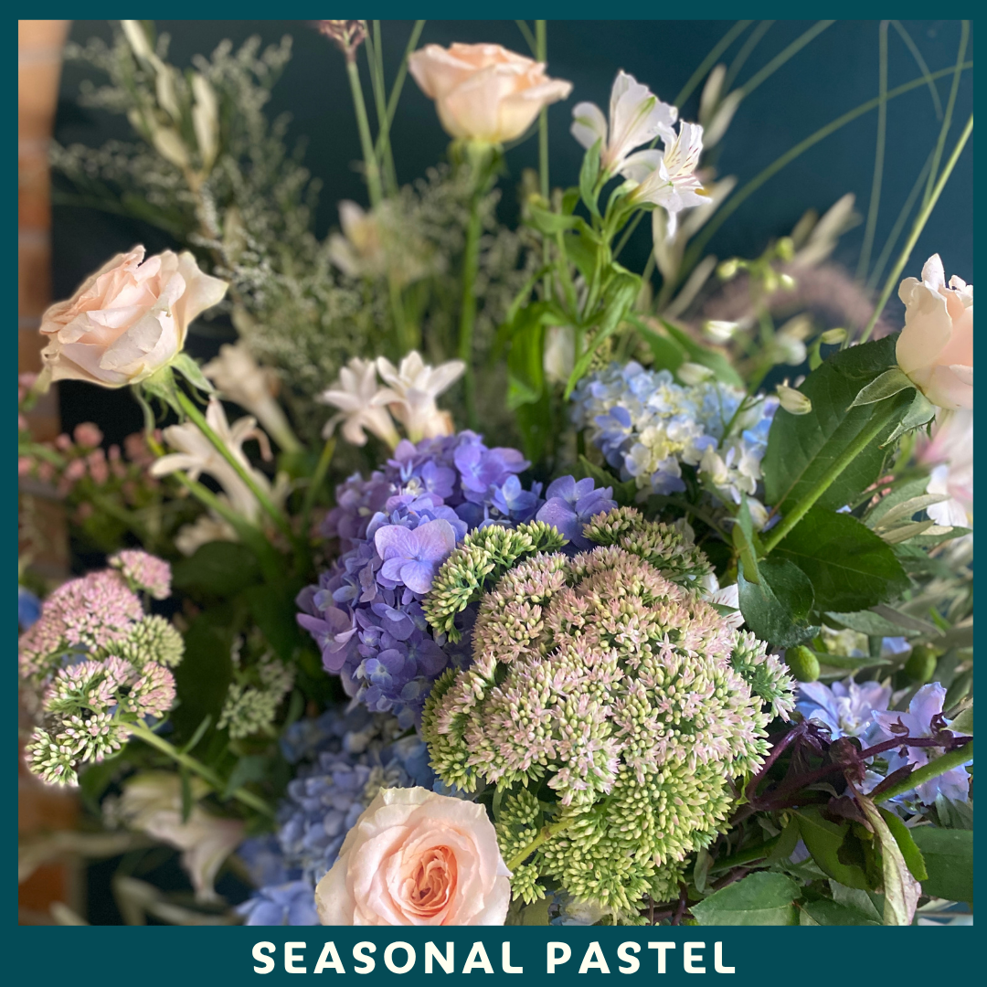 Seasonal pastel flower arrangement with a focus on hydrangeas and roses.