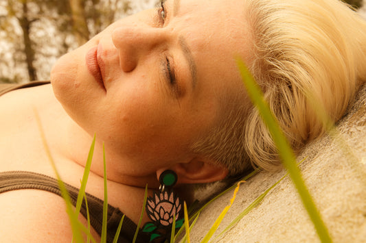 Doodad and Fandango designed earrings on a model, showing a pink waratah or protea.