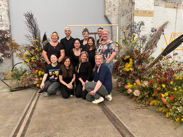 Suz and a group of people who attended a Bold Botanicals workshop, surrounded by large arrangements of native Australian flowers
