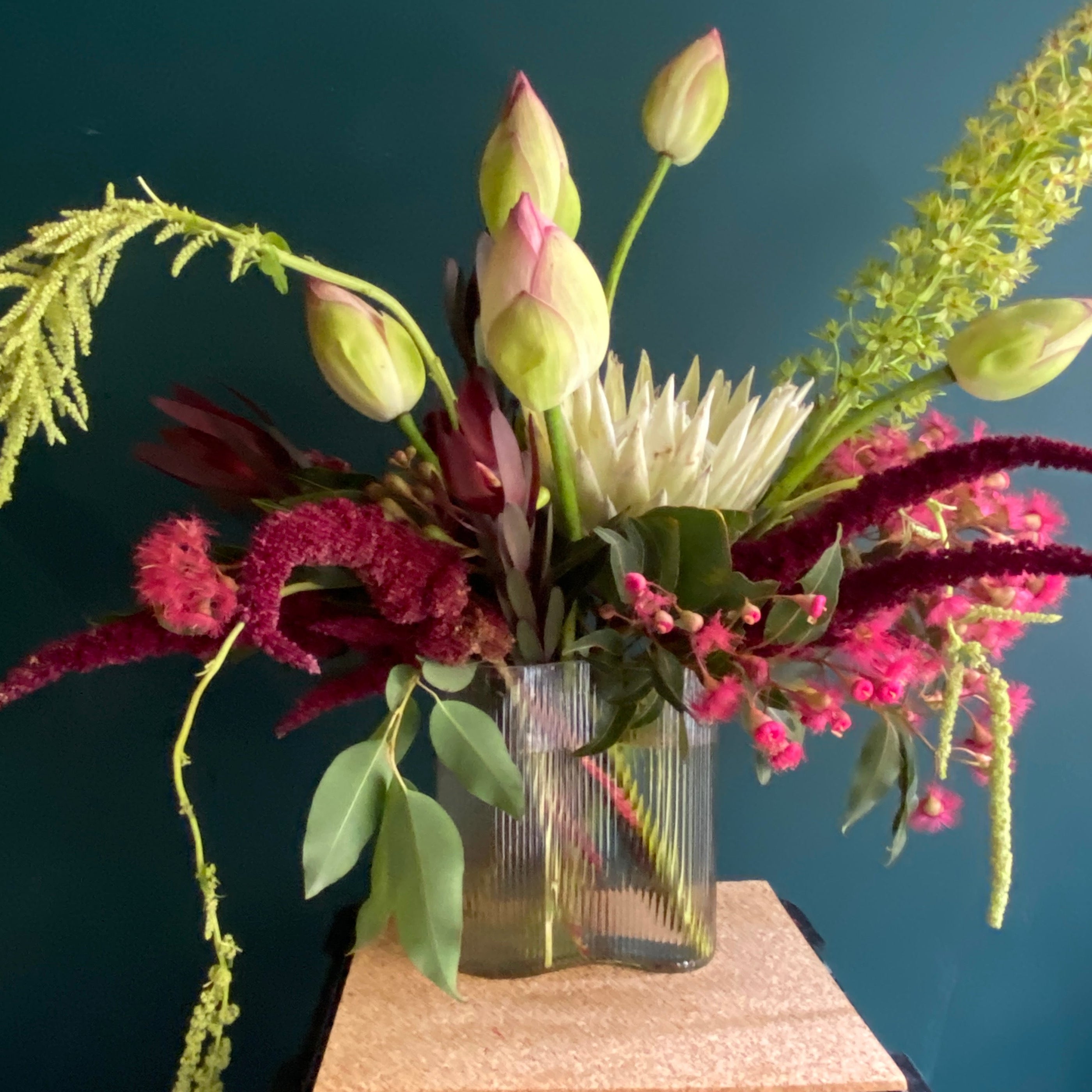 A bold flower design in a vase featuring lotus flowers, pink flowering gum and red amaranthus
