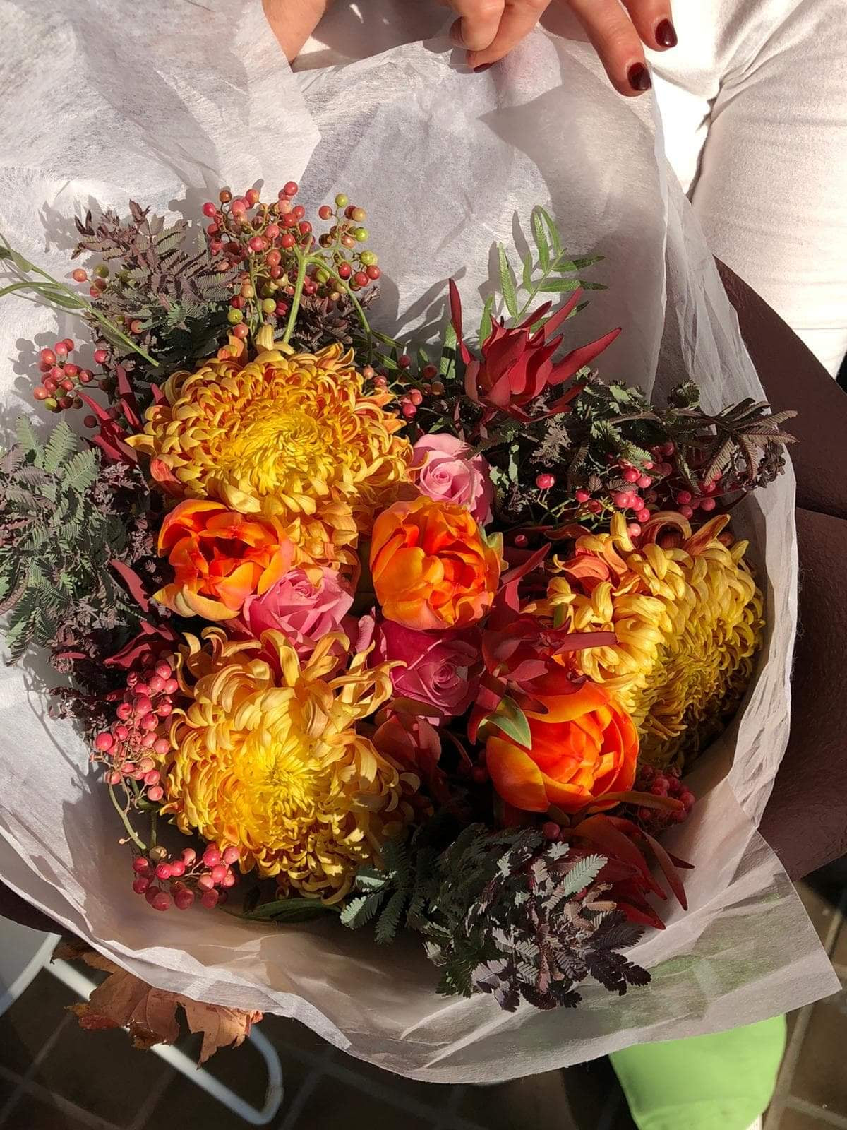 Golden hued Autumn flowers of Chrysanthemums, wattle foliage and Tulips, wrapped in a bouquet