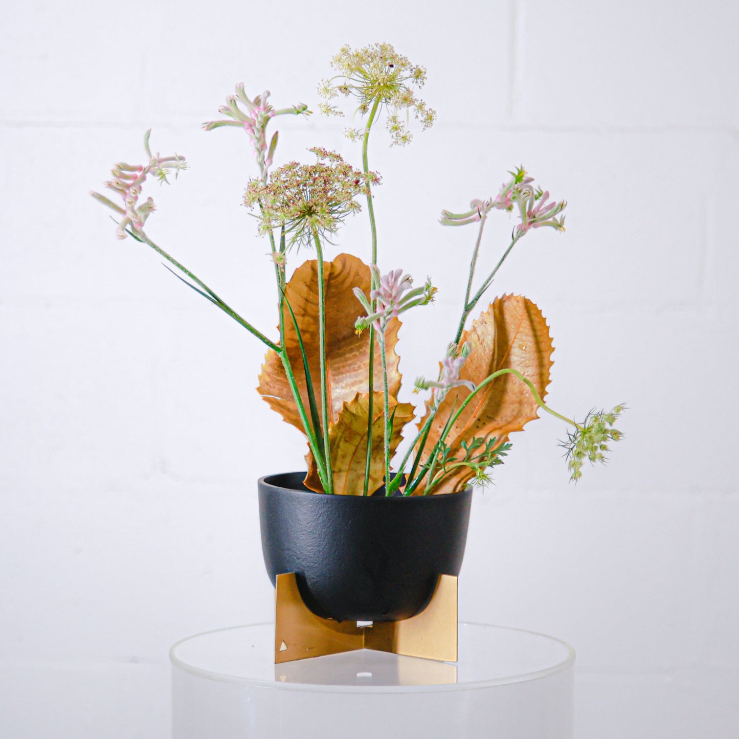 Black and gold metal pot from Marble Basics with a delicate flower arrangement