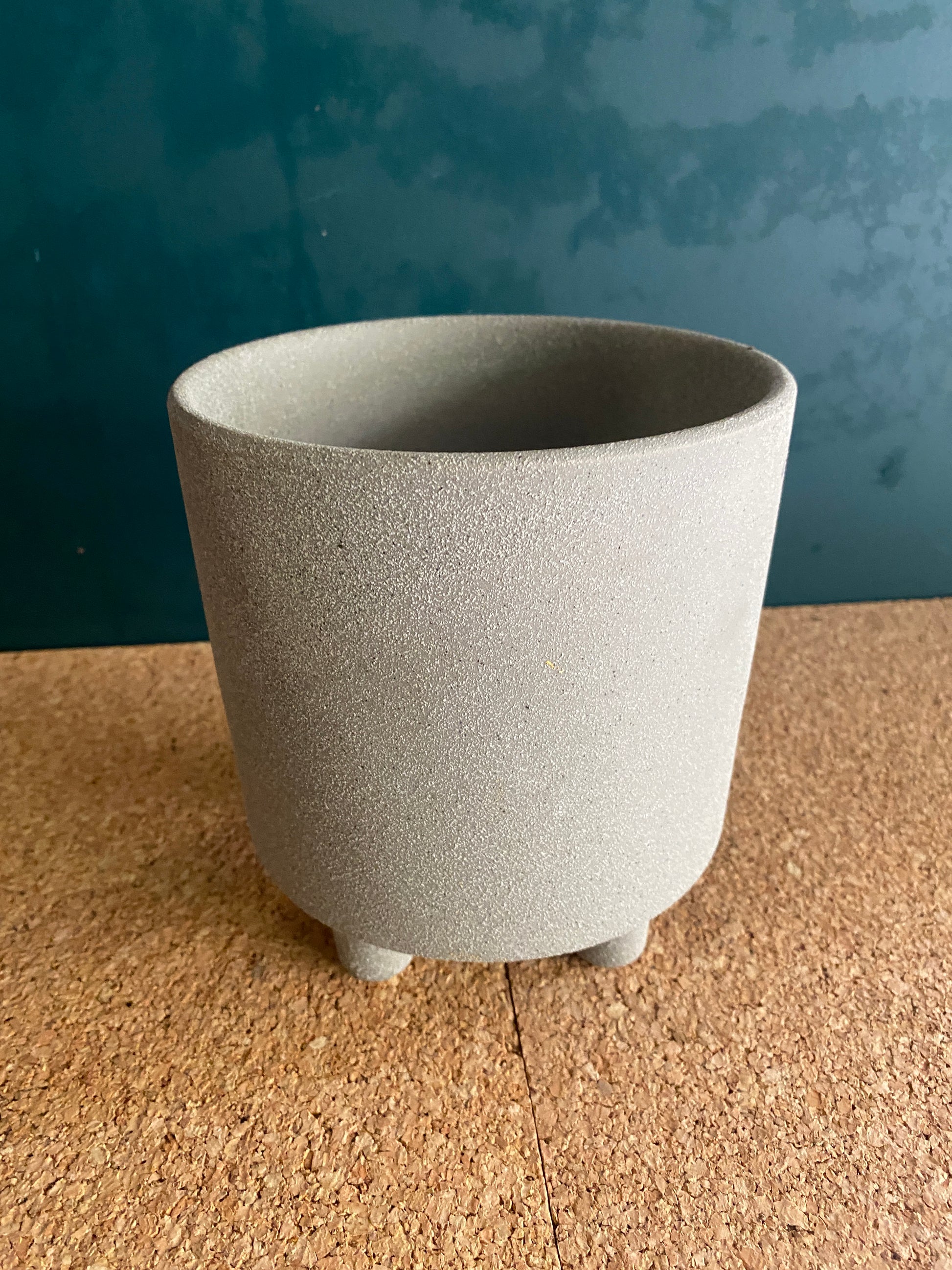 Grey concrete footed pot for plant with sandy texture