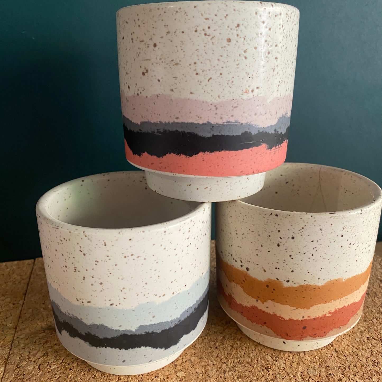 A stack of three glazed small succulent pots in bright colours and terrazzo look finish