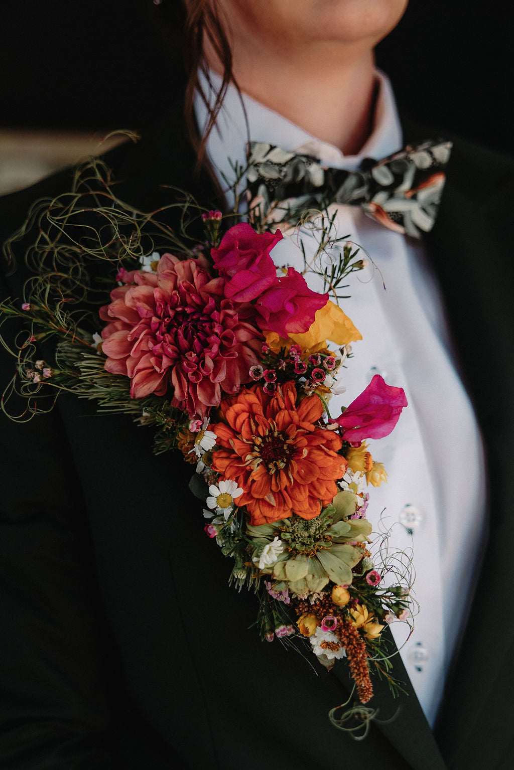 A large, colourful wedding buttonhole made with a combination of yellow, red and orange flowers