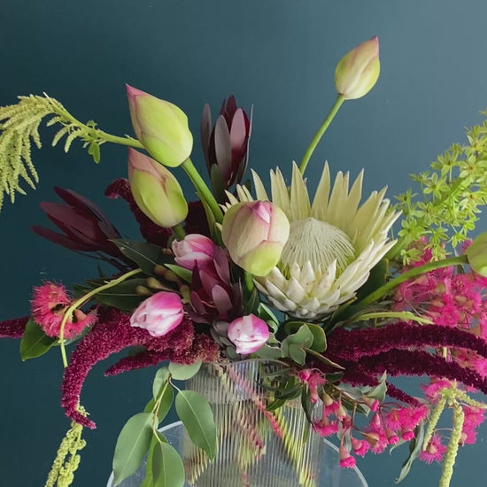 A bold flower design in a vase featuring lotus flowers, pink flowering gum and red amaranthus