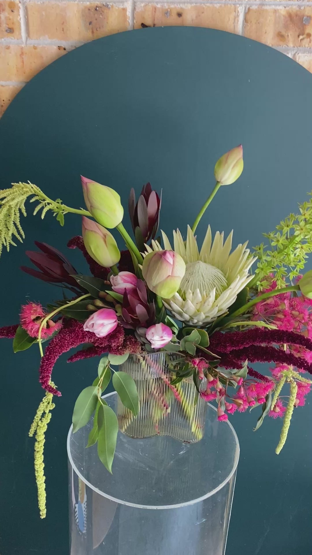 A bold flower design in a vase featuring lotus flowers, pink flowering gum and red amaranthus